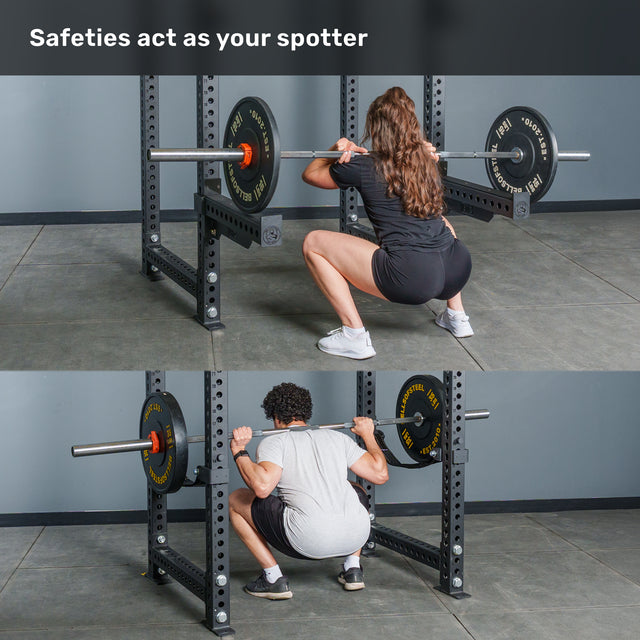 A man and a woman perform squats with barbells inside the Bells of Steel Manticore Four Post Power Rack - Prebuilt (3" x 3", 1" Holes) at the gym. Safety bars are positioned at knee height to catch the barbell if needed. Text above reads, "Safeties act as your spotter.