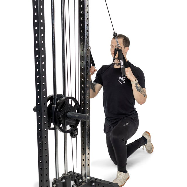 Wearing athletic clothing, a person performs a half-kneeling row on a cable machine, pulling Bells of Steel Adjustable Length Aluminum Handles toward their chest. The background is plain white.