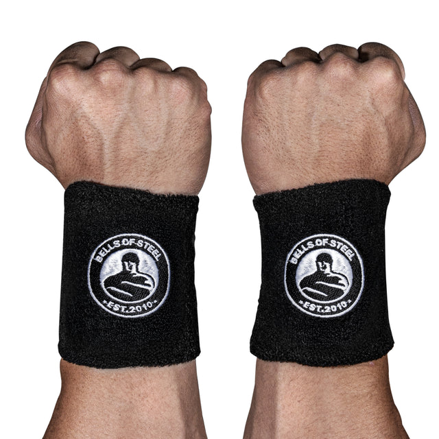 Two fists display BellGuard Kettlebell Wrist Guards by Bells of Steel, black with a white logo and “EST. 2010” embroidery—ideal protection for serious kettlebell lifters.