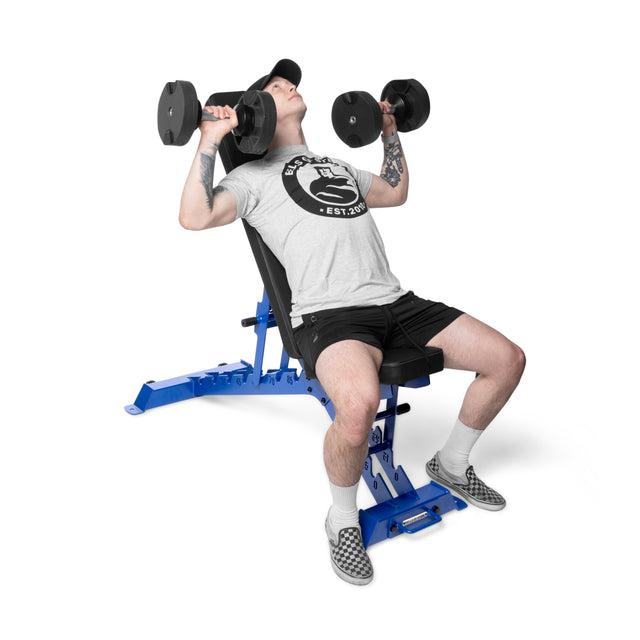 A person in a white T-shirt and black shorts lifts dumbbells on a Buzz-Saw Heavy-Duty Adjustable Bench by Bells of Steel. The blue bench complements their black cap and black and white checkered shoes.