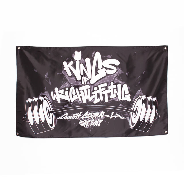 A black Bells of Steel Flag featuring graffiti-style "Kings of Weightlifting" text above barbells and "South Central LA 2017" below—bold gym decor to add attitude to your home workout setup.