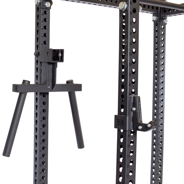 Close-up of the Bells of Steel black metal power rack with adjustable J-cups and a Y Dip Bar Rack Attachment for versatility. The grid of holes allows customizable accessory placement, while visible screws ensure sturdy construction.
