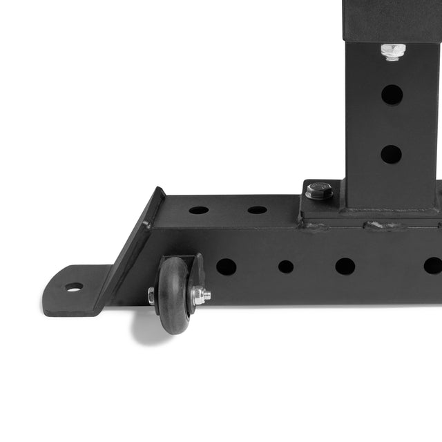 Close-up of the black metal frame of the Bells of Steel Powerlifting Flat Bench, showing its robust design with a caster wheel, multiple circular holes, and a horizontal bracket. It boasts a sturdy build supporting up to 1,000 lbs.