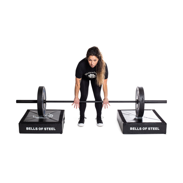 A woman prepares to lift a barbell supported by Bells of Steel Deadlift Pads (Pair) against a white background.