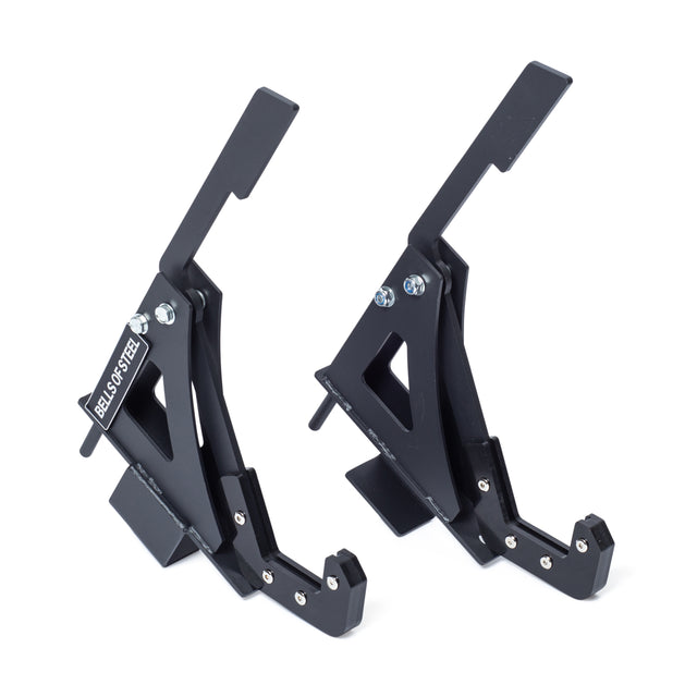 Two black Monolift Rack Attachments by Bells of Steel, featuring angular designs, UHMW plastic liners, and bolts. These space-saving barbell holders are shown upright on a white background.