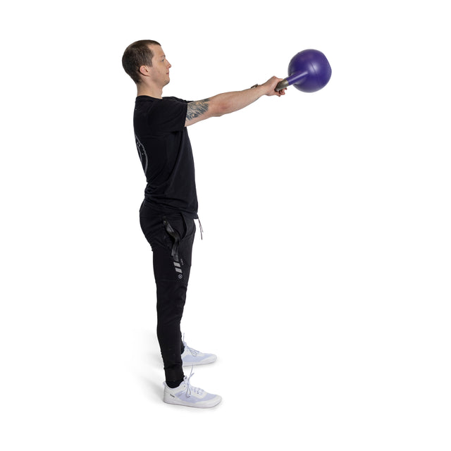 A man in black workout clothes performs a kettlebell swing using an Adjustable Competition Kettlebell from Bells of Steel. He stands on a white background, facing left, with arms extended forward and knees slightly bent.