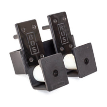 Two black plastic Bells of Steel Roller J-Cups, designed for barbell protection, each hold a white ping pong ball and are displayed side by side on a white background.