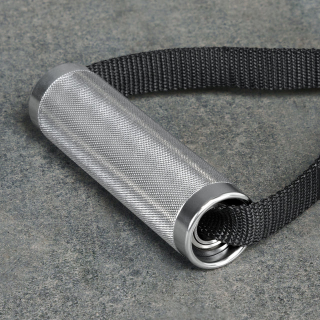 The Bells of Steel Aluminum Handles Pair with Bearings features a knurled metal grip, silver end caps, and attaches to a thick black strap, shown resting on a gray stone surface—ideal as a gym handle attachment.