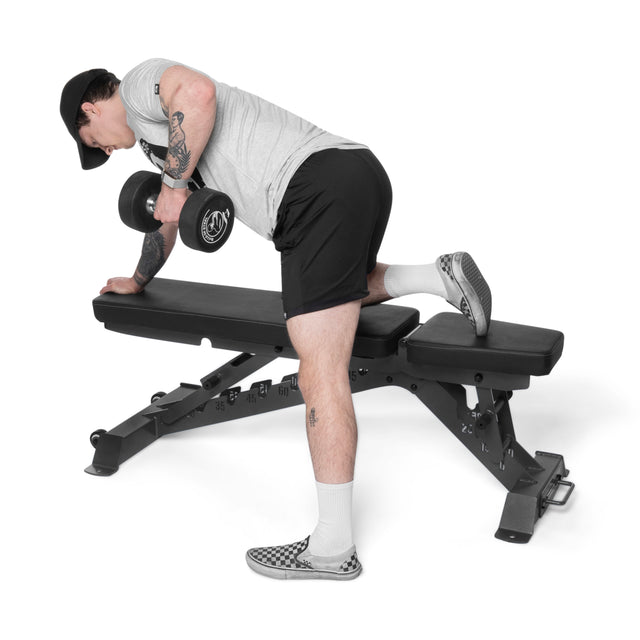 Wearing athletic gear, a person performs a one-arm dumbbell row on the Bells of Steel Buzz-Saw Heavy-Duty Adjustable Bench, supporting themselves with one knee and hand while lifting a dumbbell with the other arm.