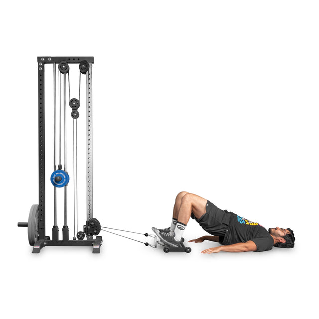 A man uses the Bells of Steel Glute Ham Slider for a posterior chain workout, lying on his back with feet on the rolling platform and hips raised in a bridge position.
