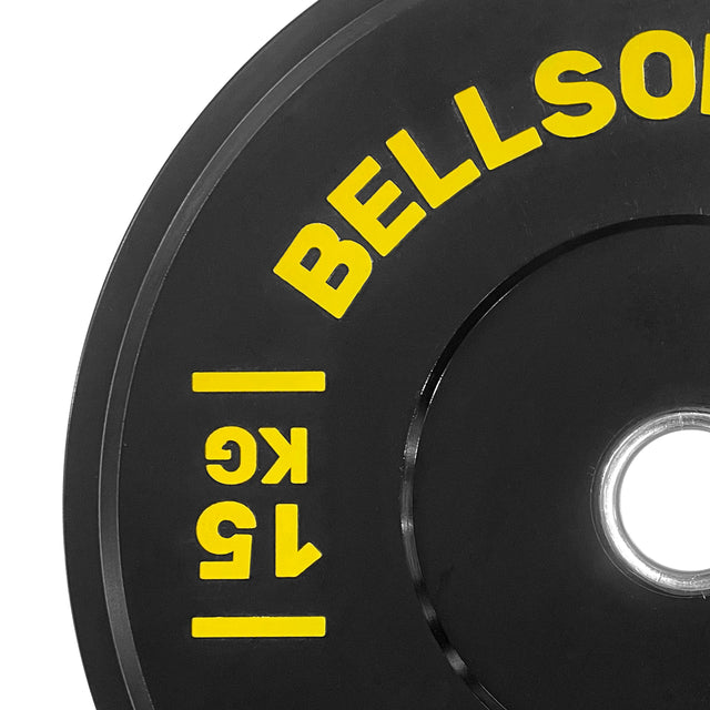 Close-up of a black Dead Bounce Conflict Bumper Plate by Bells of Steel with yellow "BELLSON" and "15 KG" text around the center hole, partially visible on a white background—ideal addition for weightlifting setups.