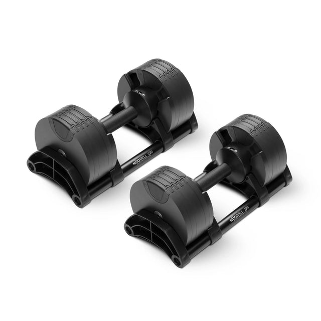 Two NÜOBELL Adjustable Dumbbells by Nuobell sit side by side on matching black bases, each with machined steel weight plates and textured handles.