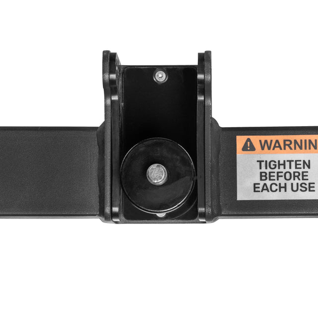 Close-up of the Bells of Steel Shoulder Boulder/Chest Fly Attachment—a black metal hinge with a central bolt, typically used as a power rack attachment. A right-side label warns, "WARNING: TIGHTEN BEFORE EACH USE." White background.