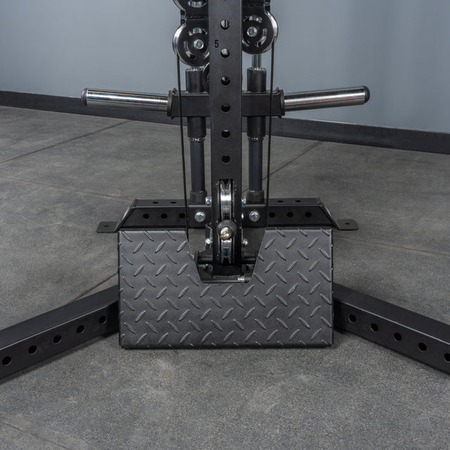 Close-up of the Bells of Steel All-in-One Trainer's black metal base with a textured diamond plate cover, bolts, and adjustable holes on a gray tiled floor—perfect for any home gym.