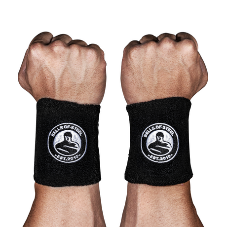 Two raised fists, each wearing a black wrist wrap with a "Bells of Steel EST. 2010" logo featuring a kettlebell graphic, against a white background.
