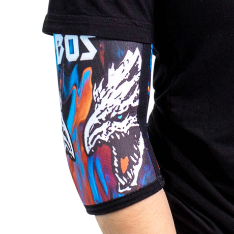 A person wearing a black shirt and a colorful arm sleeve featuring a fierce white dragon head design with an open mouth on a blue and orange background.