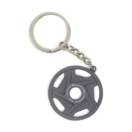 A metallic keychain with a circular, weight plate-shaped charm that has star-shaped cutouts and "BELLS OF STEEL" printed on it, attached to a metal chain and key ring.