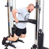 A man in a gray t-shirt and black shorts performs dips on Bells of Steel Cable Tower Squat Stands with a dip bar attachment, against a white background.