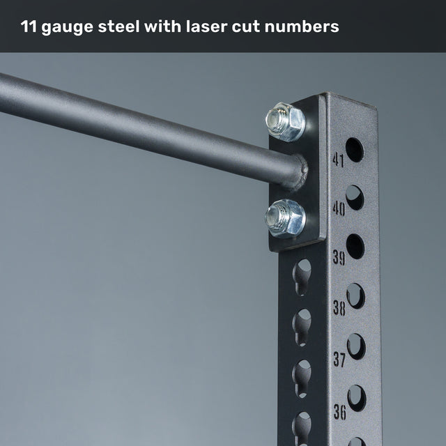 Close-up of the Bells of Steel Manticore Squat Stand - Prebuilt, constructed from durable 3" x 3" 11-gauge black steel uprights with precise laser-cut numbered 1" holes and a horizontal bar secured by bolts—perfect for any home gym. Text at the top reads, "11 gauge steel with laser cut numbers.