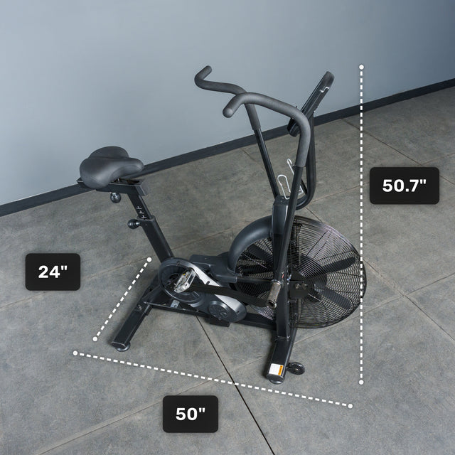 A black Bells of Steel Residential Air Bike with Wind Guard, featuring a prominent fan wheel, sits on a gray floor. Its dimensions are labeled: 50.7" tall, 24" wide, and 50" long—ideal for any home gym.