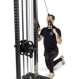 Wearing athletic clothing, a person performs a half-kneeling row on a cable machine, pulling Bells of Steel Adjustable Length Aluminum Handles toward their chest. The background is plain white.