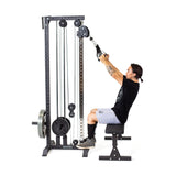 A person uses the Bells of Steel Cable Tower, sitting on a bench and performing a lat pulldown with adjustable handles. The machine features a weight stack and adjustable pulleys, set against a white background.