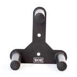 The Bells of Steel Change Plate Storage Pegs is a black metal wall mount with three cylindrical pegs in a triangular layout for holding Olympic change plates. It features two mounting holes and an upside-down "SIS" logo at the base.