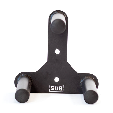 The Bells of Steel Change Plate Storage Pegs is a black metal wall mount with three cylindrical pegs in a triangular layout for holding Olympic change plates. It features two mounting holes and an upside-down "SIS" logo at the base.