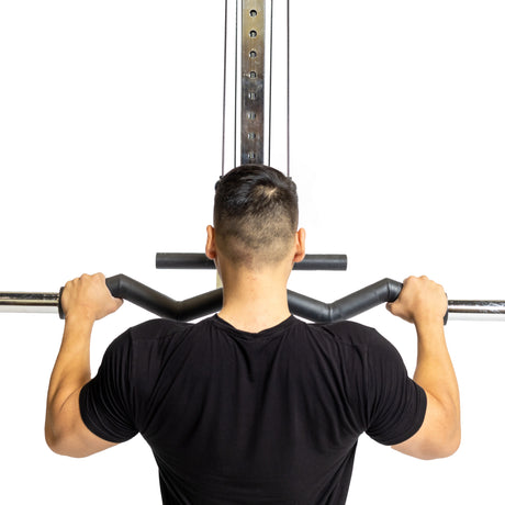 A person in a black shirt is seen from behind using the Fat Bar - Olympic Curl Bar Cable Attachment by Bells of Steel. Set against a white background, they grip the bar firmly with both hands to enhance grip strength during the exercise.