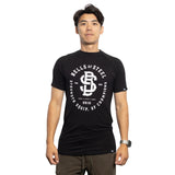 A person faces forward in a black Bells of Steel Bamboo T-Shirt with white graphics and dark pants, standing against a plain white background.