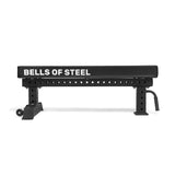 The Powerlifting Flat Bench by Bells of Steel is a black adjustable exercise bench with a sturdy steel frame and multiple adjustment holes for different heights. It features a flat, padded surface ideal for weightlifting and other fitness routines.