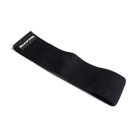 The Bells of Steel Glute Loop is a black non-slip resistance band featuring the brand’s white text on one end, laid flat on a white background—ideal for intense glute workouts.