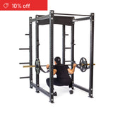 A person in black workout attire performs a barbell squat inside the Bells of Steel Hydra Six Post Power Rack Builder (3" x 3", ⅝" Holes); a red "10% off" banner appears in the top left corner.