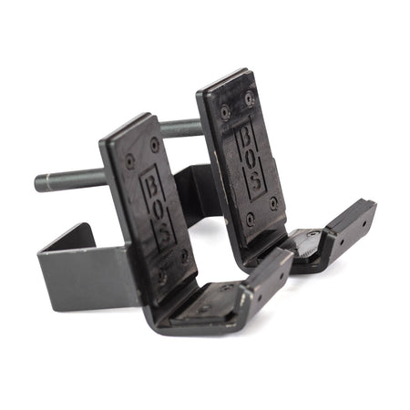 The Bells of Steel Standard J-Cups are two black metal, wall-mounted hooks with "BOS" engraved plates, featuring L-shaped bases and a connecting rod for secure holding, designed for power racks.