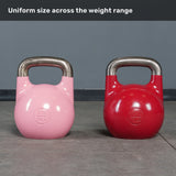 Two Bells of Steel Competition Kettlebells—one pink (8 kg/18 lb) and one red (32 kg/71 lb)—rest side by side on a gym floor. The text above says, “Uniform size across the weight range.” These kettlebells feature an identical size, adhering to the competition standard for consistent training.