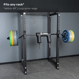 The Bells of Steel Safety Squat Bar – The SS4, loaded with plates, sits on a black power rack in a gym with gray walls and floor. Text above reads: “Fits any rack* *Within 49'' j-cup outer edge.” Perfect for crushing leg day.