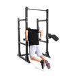 A person in a black shirt and gray shorts performs dip exercises on Bells of Steel's Manticore Half Rack - Prebuilt (3" x 3", 1" Holes), set up against a white background for a home gym.