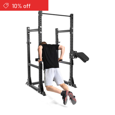 A person in black and gray does dips on the Bells of Steel Manticore Half Rack Builder (3" x 3", 1" Holes). A "10% off" sale banner appears top left on a white background—the perfect home gym upgrade.