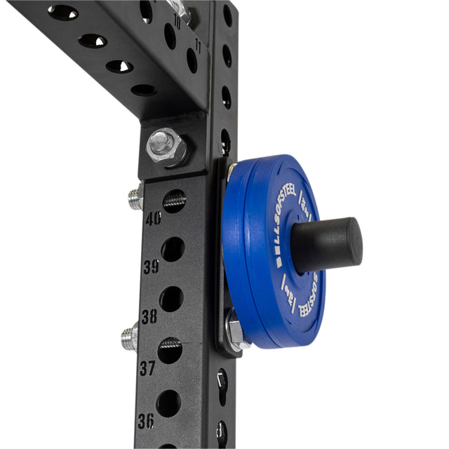Close-up of the Bells of Steel Bolt-On Plate Pegs loaded with blue Olympic-sized weight plates on a black metal frame. The power rack includes numbered holes and bolts for adjustable settings, ensuring precision during workouts.