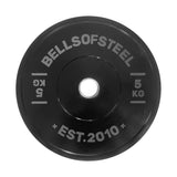 A black Dead Bounce Conflict Bumper Plate by Bells of Steel, labeled "5 KG," "KG," and "EST. 2010" in white, with a central hole for weightlifting bars.