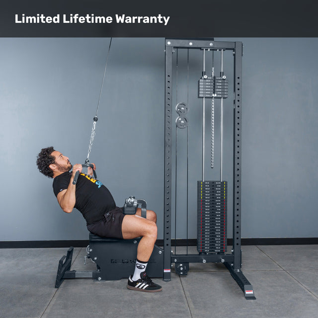 A man uses the Bells of Steel Lat Pulldown Low Row Machine with weight stack and pulleys in a gym, performing a lat pulldown. Text at the top reads "Limited Lifetime Warranty.
