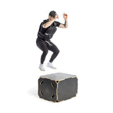 A person in athletic gear, including a cap and a Bells of Steel Weighted Vest, is captured mid-jump onto a black platform marked "20 18-24" in a brightly lit, white studio.